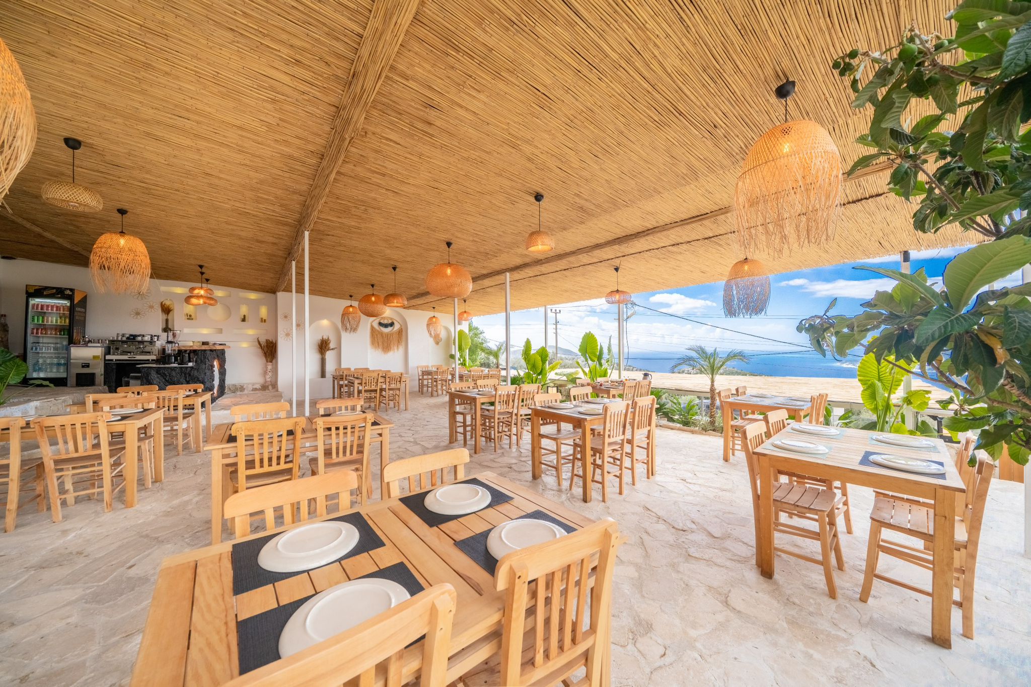 Interior of a restaurant with wooden tables and chairs, a marble floor, and a terrace overlooking the sea. Sample Size: 19...